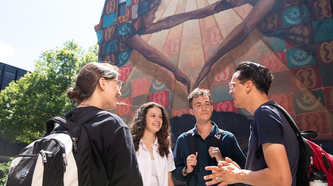 Duquesne students chatting in front of mural on A-Walk